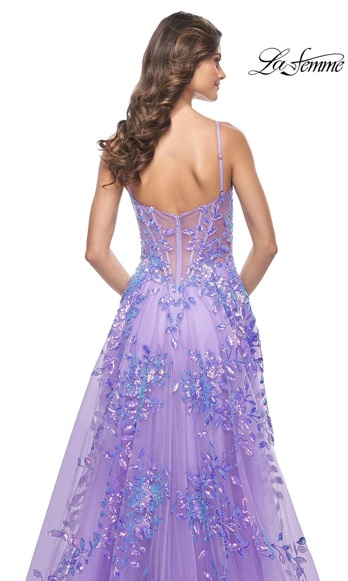 A woman with long wavy hair is seen from the back wearing the La Femme Sequin-Print Long A-Line Prom Dress 32223, featuring thin straps, a sheer bodice, and a flowing skirt in a formal style.